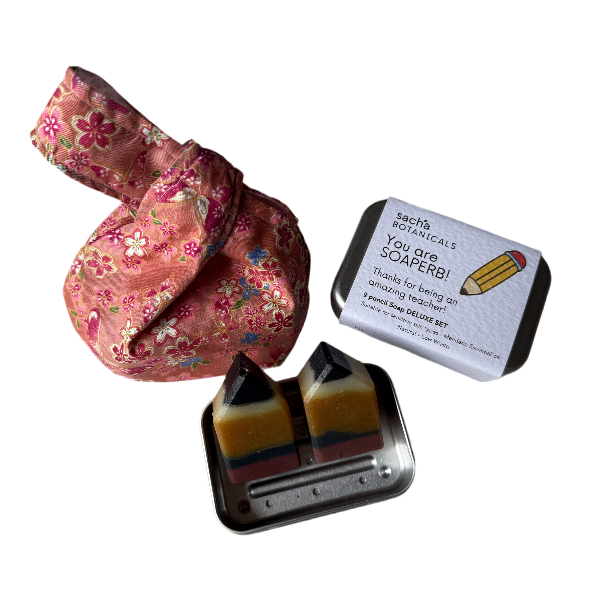 Set of three soap bars in a metal holder with a handmade floral pouch and a card on a white background